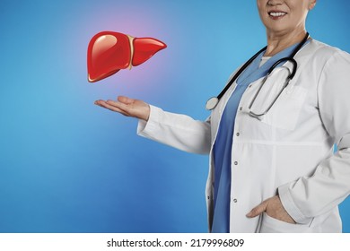 Mature doctor with stethoscope and illustration of healthy liver on light blue background, closeup