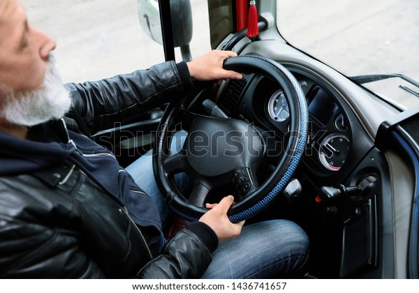 Mature driver sitting in cab of modern truck,\
closeup view