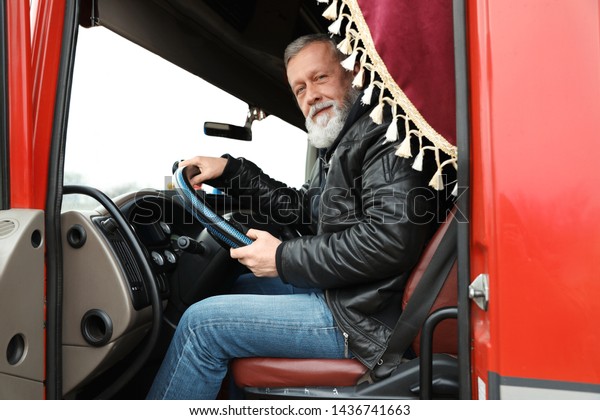 Mature driver\
sitting in cab of modern\
truck