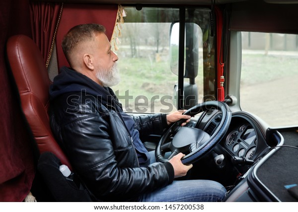 Mature driver\
sitting in cab of modern\
truck