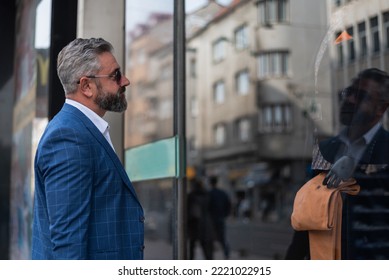 A Mature Elegant Business Man Choosing A Suit In Mall Or Clothing Store While Looking At The Shop Window.