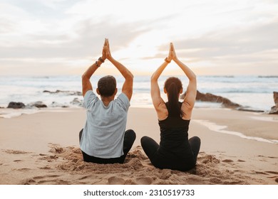 Mature european couple in sportswear practice yoga, sit, meditate, enjoy workout together in morning on sea beach, back, outdoor. Sports and peace, fitness and body care, mental health - Shutterstock ID 2310519733