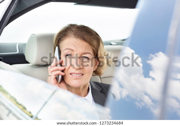 Mature executive\
talking on smartphone in\
car