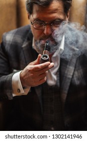 Mature Experienced Caucasian Professor Wears Tweed Jacket, Looks Confidently, Has Clever Intelligent Expression While Puffing Pipe. People, Wisdom And Age Concept