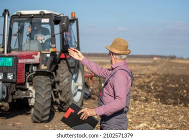 Mature farmer driving tractor and talking to a senior man in field - Powered by Shutterstock