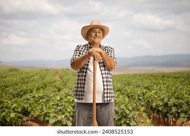 Mature farmer leaning on a shovel on a vineyard - Powered by Shutterstock