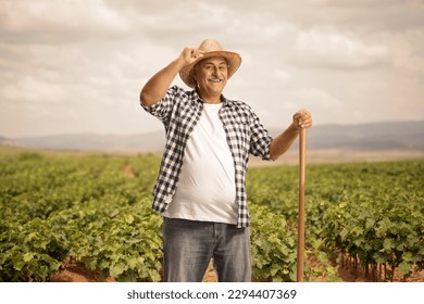 Mature farmer on a grapevine field greeting with his straw hat - Powered by Shutterstock