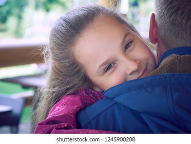 Mature father embraced by his daughter, smiling and laughing together at the terrace cafe. Happy family moments, father and daughter relationship concept