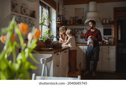 Mature father with two small children washing dishes indoors at home, daily chores concept. - Powered by Shutterstock