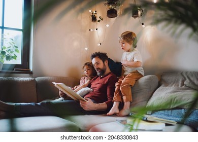 Mature father with two small children resting indoors at home, looking at photo album. - Powered by Shutterstock