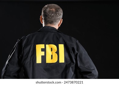 Mature FBI agent on black background, back view