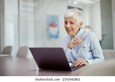 Mature Female CEO Using Laptop While Working In The Office.