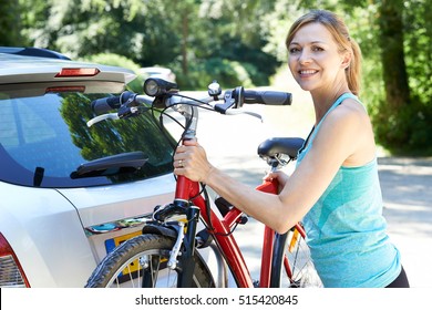 Mature Female Cyclist Taking Mountain Bike From Rack On Car