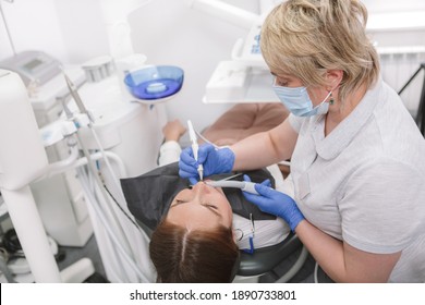 Mature Female Dentist Treating Teeth Of Female Patient