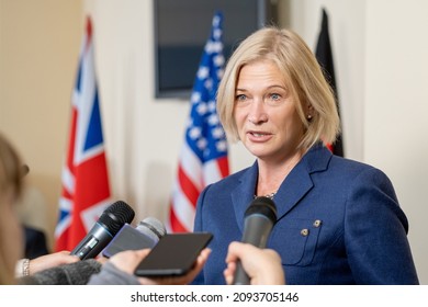 Mature female deputy in elegant suit speaking in microphones of journalists at press conference after political event - Shutterstock ID 2093705146