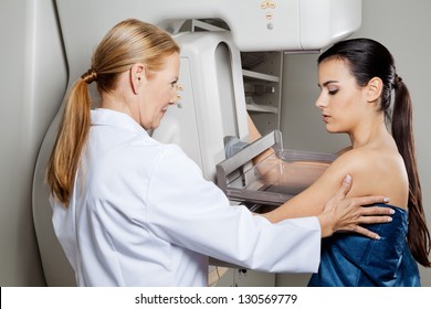 Mature female doctor assisting young patient undergoing mammogram