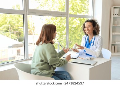 Mature female doctor prescribing pills to patient in clinic - Powered by Shutterstock