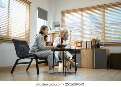 Mature female doctor showing anatomical model of spine, educating female patient in consultation room - Powered by Shutterstock