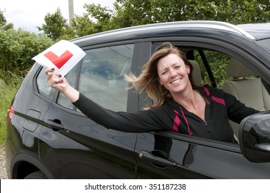 Mature female driver smiling & holding a learner L plate