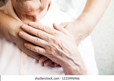 Mature female in elderly care facility gets help from hospital personnel nurse. Senior woman, aged wrinkled skin & hands of her care giver. Grand mother everyday life. Background, copy space, close up