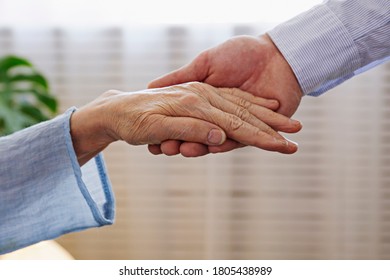 Mature Female In Elderly Care Facility Gets Help From Hospital Personnel Nurse. Close Up Of Aged Wrinkled Hands Of Senior Woman Reaching To A Male Doctor. Copy Space, Background