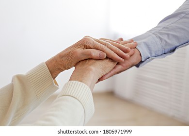 Mature Female In Elderly Care Facility Gets Help From Hospital Personnel Nurse. Close Up Of Aged Wrinkled Hands Of Senior Woman Reaching To A Male Doctor. Copy Space, Background