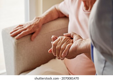 Mature female in elderly care facility gets help from hospital personnel nurse. Senior woman with aged wrinkled skin and care giver, hands close up. Grand mother everyday life. Background, copy space.