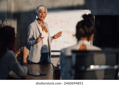 A mature female executive having presentation with her creative female team at corporate office. Senior businesswoman having briefing with with team of experts at boardroom and discussing project. - Powered by Shutterstock