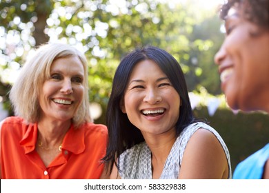 Mature Female Friends Socializing In Backyard Together