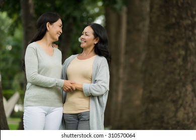 Mature Female Friends Talking While Walking In The Park