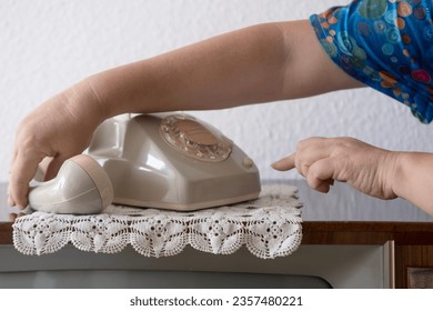 mature female hand removing Handset, rotating Dialer on Old white Rotary Telephone with Disc Dial with finger, putting retro phone reciver down, hanging up, calls helpline, psychological support