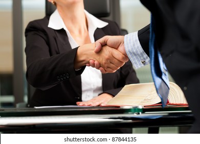 Mature female lawyer or notary with client in her office - handshake