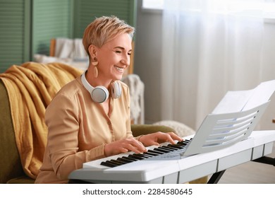 Mature female musician playing synthesizer at home - Powered by Shutterstock