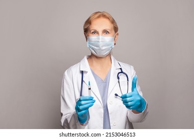 Mature Female Nurse Or Doctor Holding Syringe And Showing Thumb Up