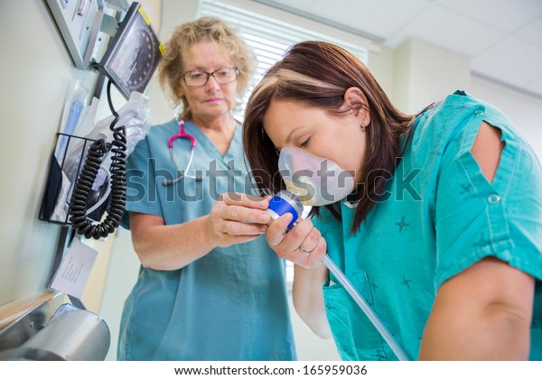 Mature female nurse woman in active labor with\
nitrous oxide mask.