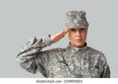 Mature Female Soldier Saluting On Grey Background