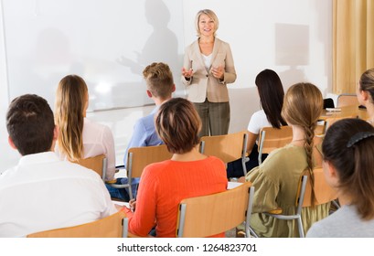Mature female speaker giving presentation for students in lecture hall 