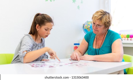 Mature female therapist working with a teenage girl with learning difficulties to master logical tests.