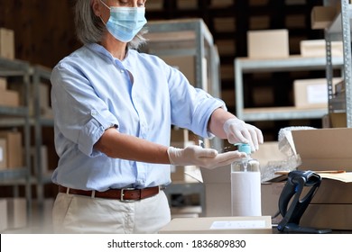 Mature female warehouse worker, post office employee, entrepreneur, small business owner wears face mask using sanitizer cleaning hands working in shipping delivery stock. Covid 19 protection, closeup - Powered by Shutterstock