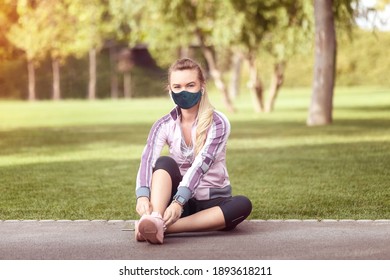 Mature Fitness Woman Wearing Face Mask Tying Shoelace Before Jogging – Smiling Female Runner Sitting On Park Track With Mobile Phone And Earphones Getting Ready To Run, Active Latin Woman Tying Shola