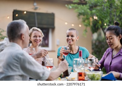 Mature Friends Enjoying Conversation Together During Dinner At Home