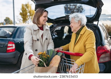 Mature granddaughter helping grandmother load groceries in to the car. Senior woman shopping at the shopping center. - Powered by Shutterstock