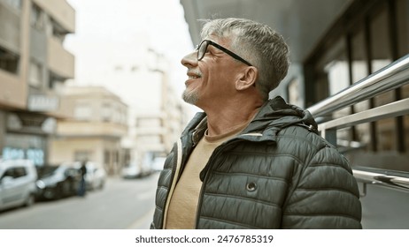 Mature grey-haired man in glasses smiles subtly while standing thoughtfully on a city street, evoking urban life. - Powered by Shutterstock