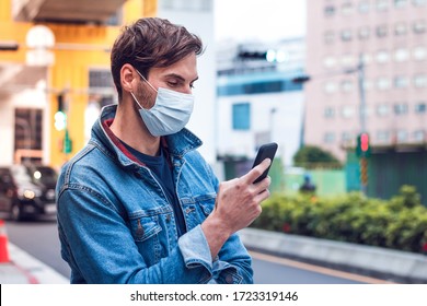 A Mature Handsome Man With A Beard Chats On His Phone And Wears A Face Pollution Mask To Protect Himself From Coronavirus.