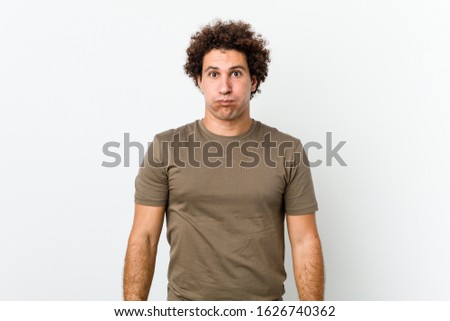 Mature handsome man isolated blows cheeks, has tired expression. Facial expression concept.