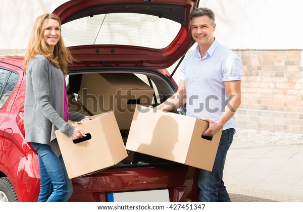 Mature\
Happy Couple Putting Cardboard Box In Car\
Trunk