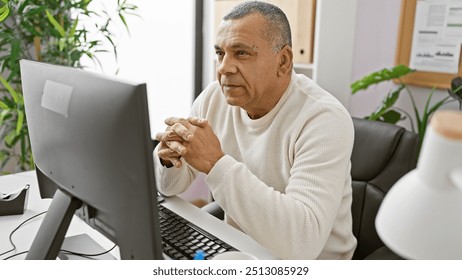 Mature hispanic man in thoughtful pose at office workplace staring at computer screen. - Powered by Shutterstock