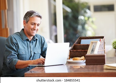 Mature Hispanic Man Using Laptop On Desk At Home - Powered by Shutterstock