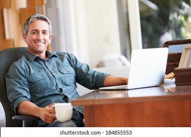 Mature Hispanic Man Using Laptop On Desk At Home