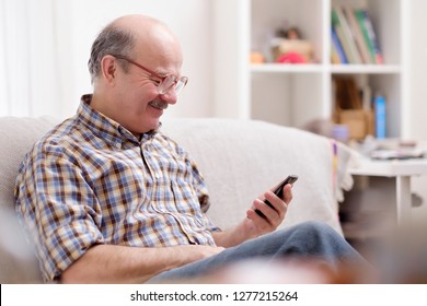 Mature Hispanic Man Wearing Eyeglasses Checking Messages On Cell Phone